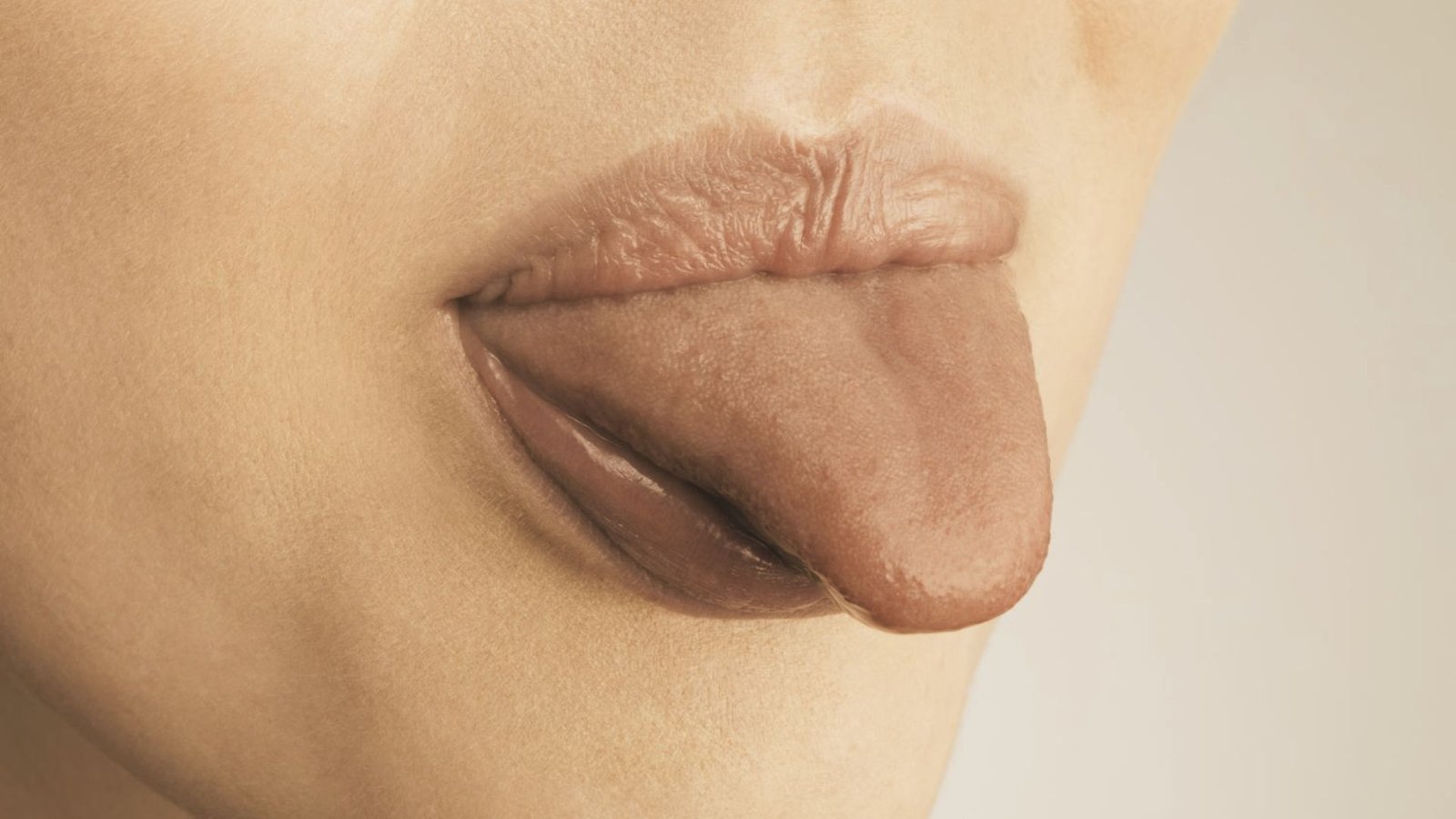 Close-up of lower face with tongue extended down over bottom lip.