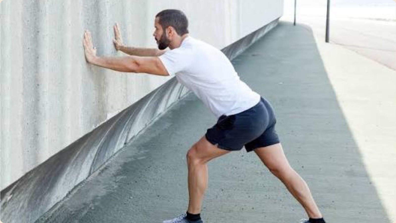 Man performing calf stretch against a wall for strength and reducing pain.