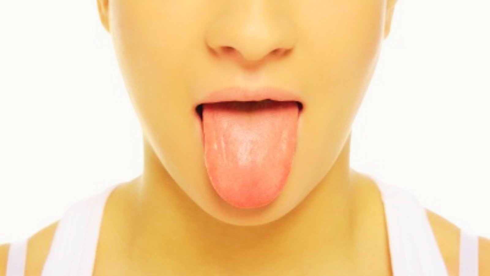 Close-up of person extending tongue straight out past the lips.