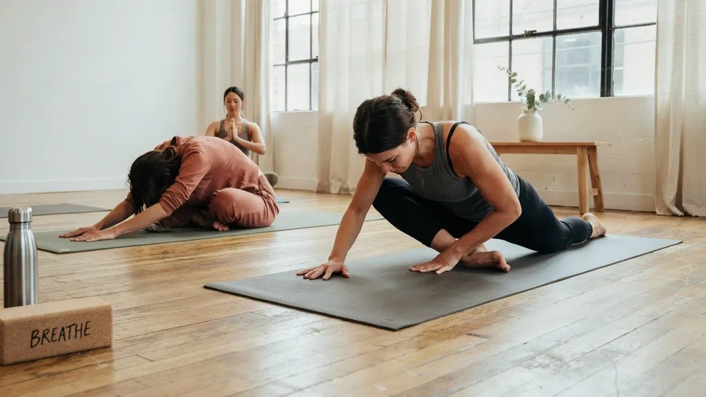 Gentle warm-up yoga poses in a heated room preparing the body for flow practice.