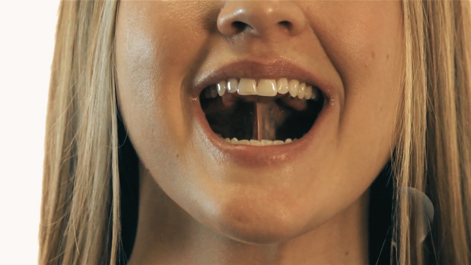 Close-up of woman with mouth open, tongue pressed against roof of mouth.