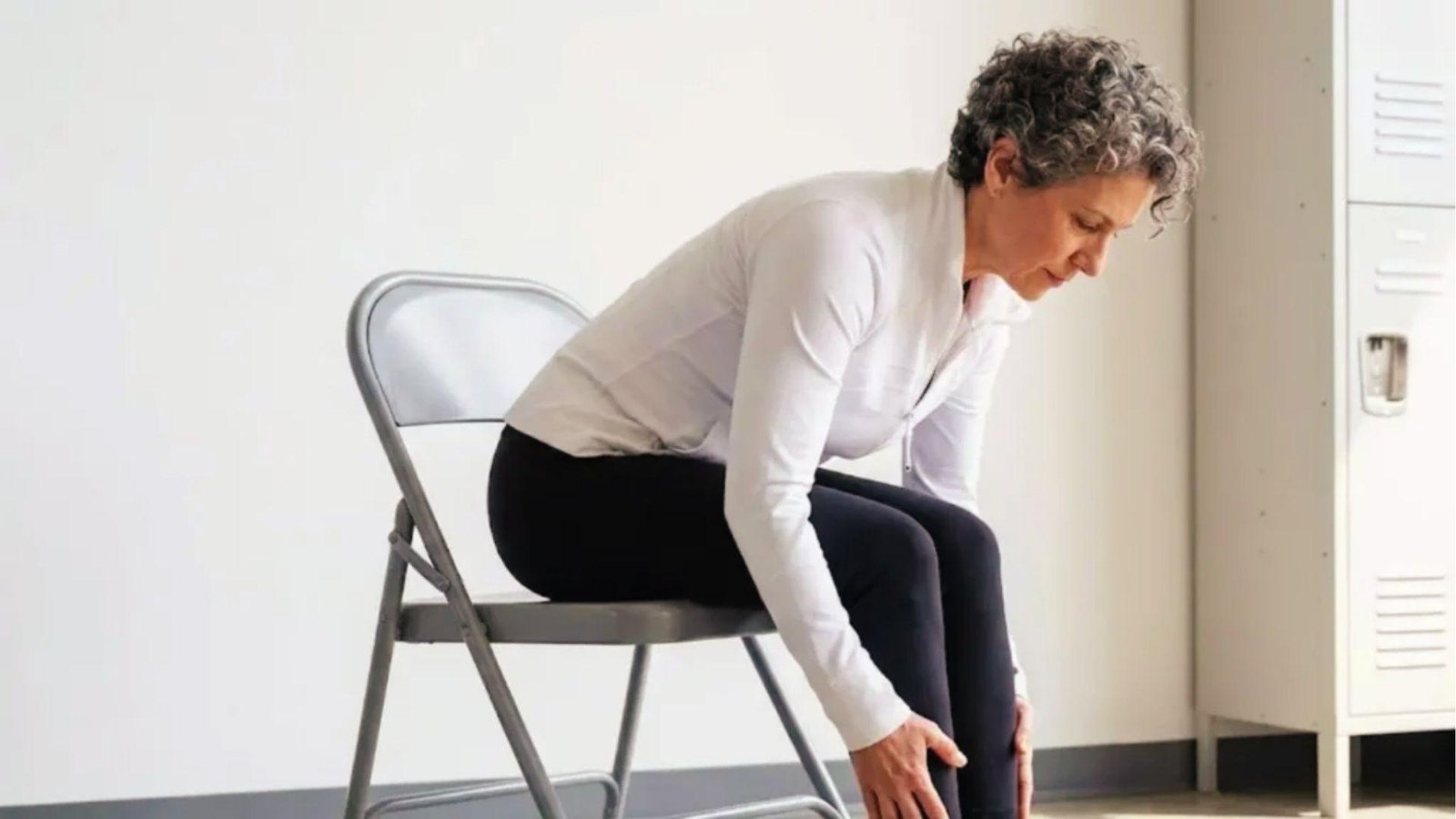 Woman leaning forward in seated chair fold stretch for 28 day chair yoga challenge routine.