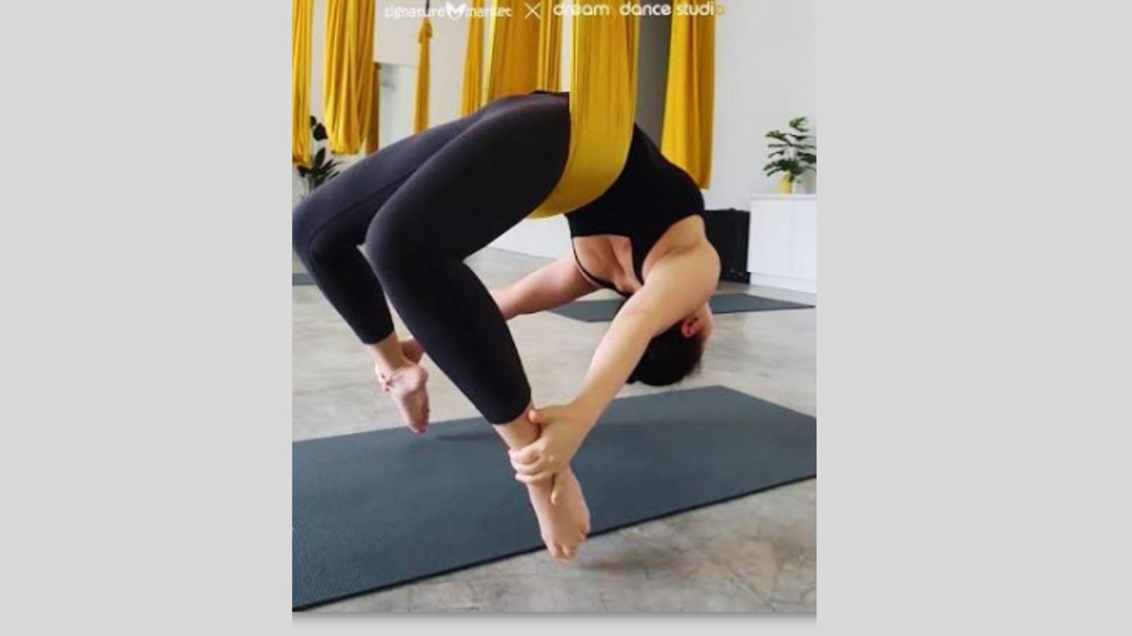 Person gently hanging upside down in a silk hammock in a beginner aerial yoga inversion.