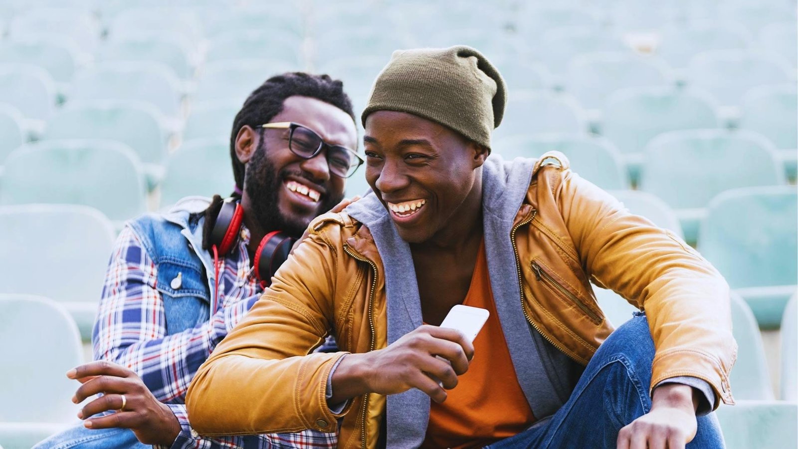 Two men laugh together in stadium seats, showing social connection and positive mood to activate parasympathetic vagus response.