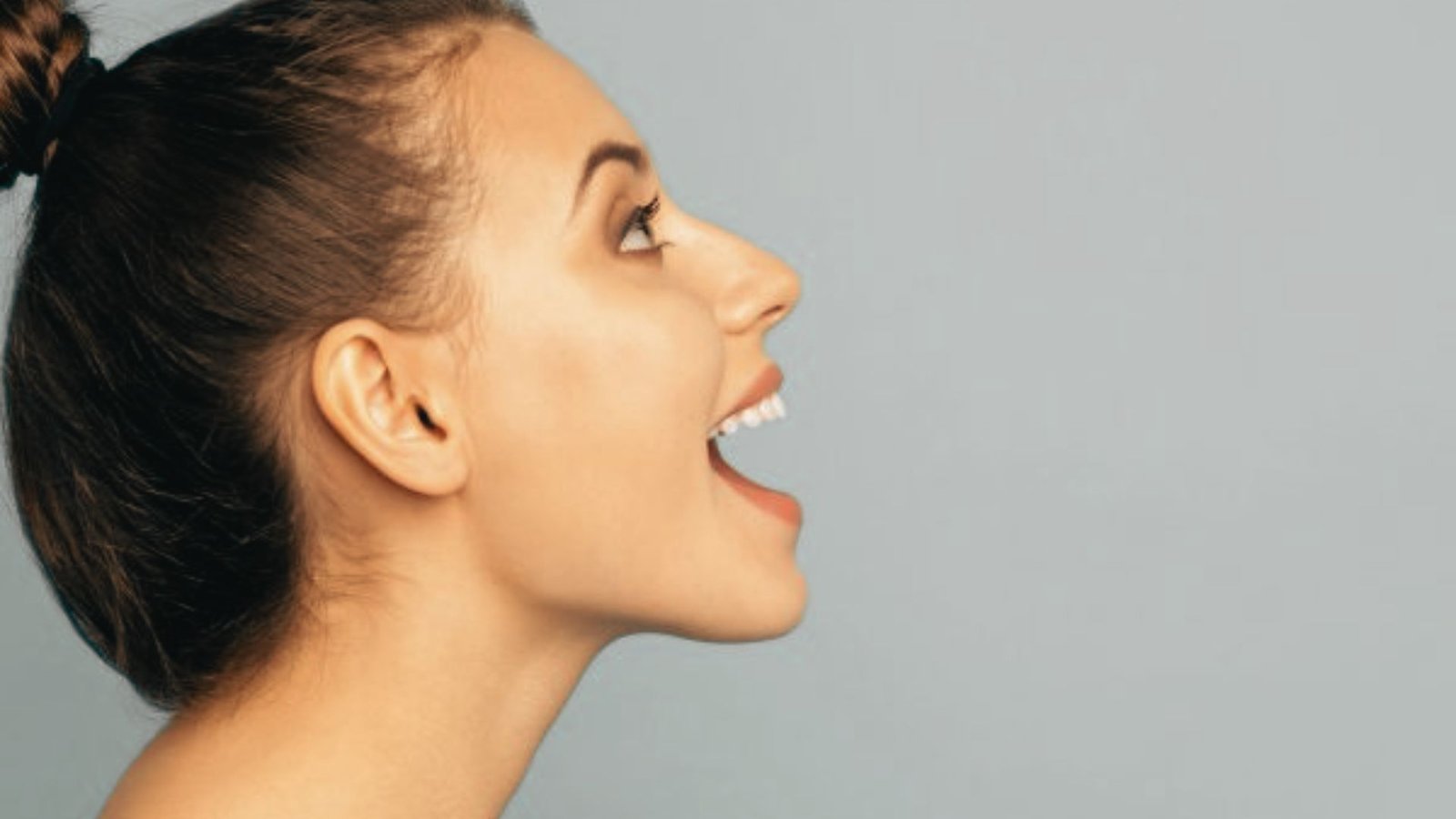 Profile of woman with mouth wide open demonstrating jaw mobility exercise.