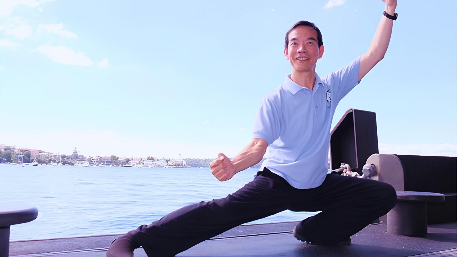 Man in light blue polo does Tai Chi lunge by waterfront, deep stance and breath to engage vagus nerve.