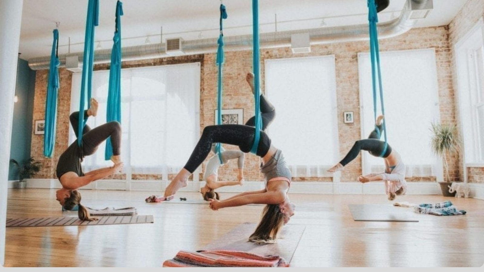 A Group of people are performing Aerial yoga