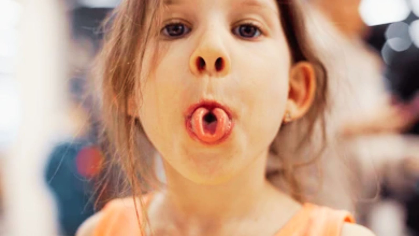 Young girl rolling her tongue into a tube shape with mouth open.