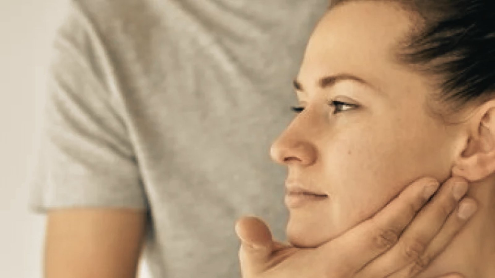 Person in profile view supports their jaw with one hand while keeping lips closed to practice correct tongue resting posture.