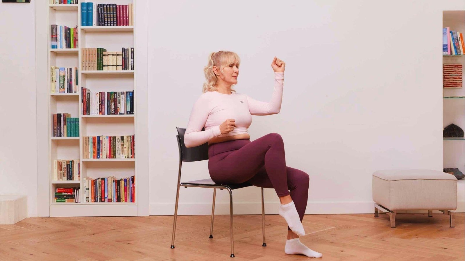 Woman doing seated march with arm curls on chair for 28 day chair yoga cardio challenge.