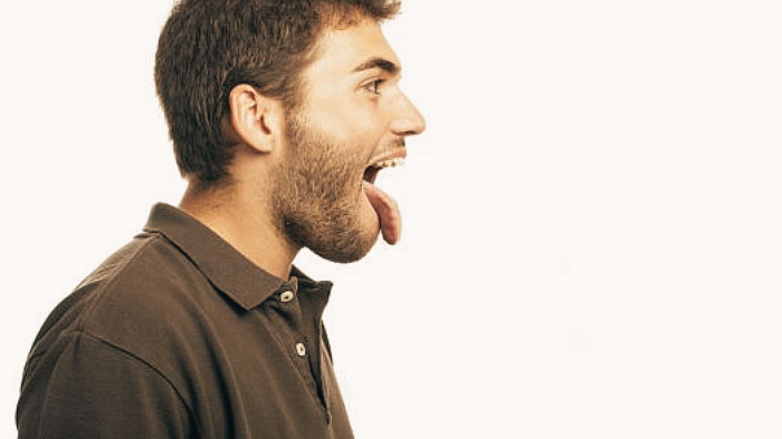 Side profile of a man extending his tongue straight out of his mouth as part of a tongue strengthening drill.