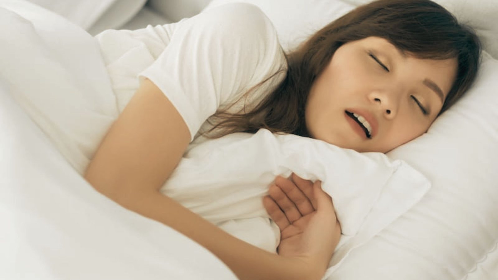 Woman sleeps peacefully on her side with her mouth slightly open, demonstrating the goal of myofunctional therapy.