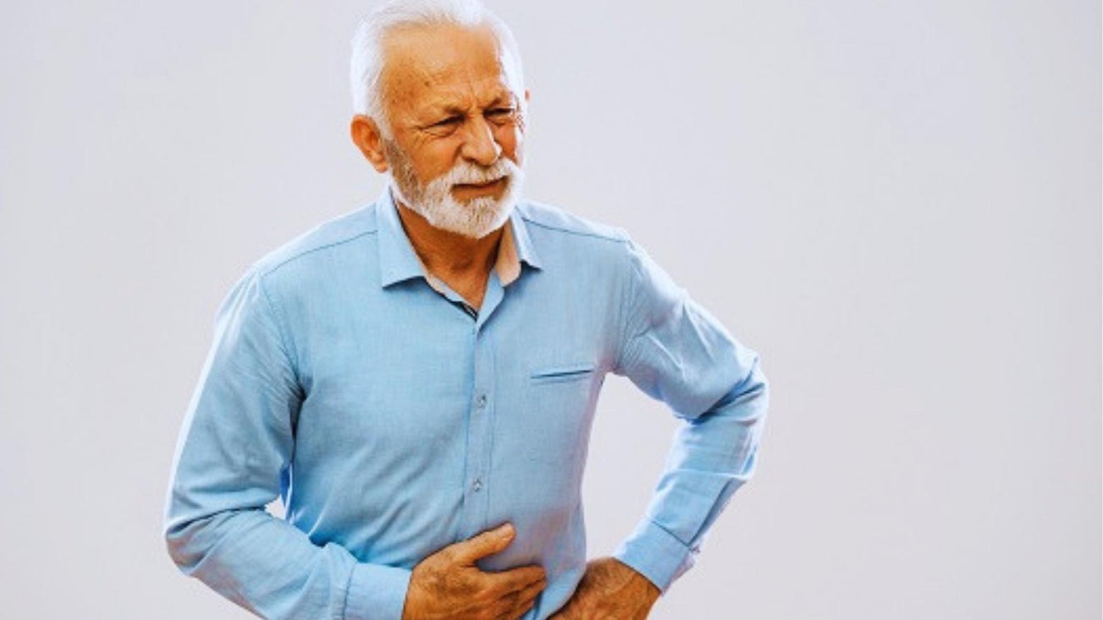 Older man in blue shirt winces and holds stomach, illustrating digestive discomfort that vagus nerve exercises may help.